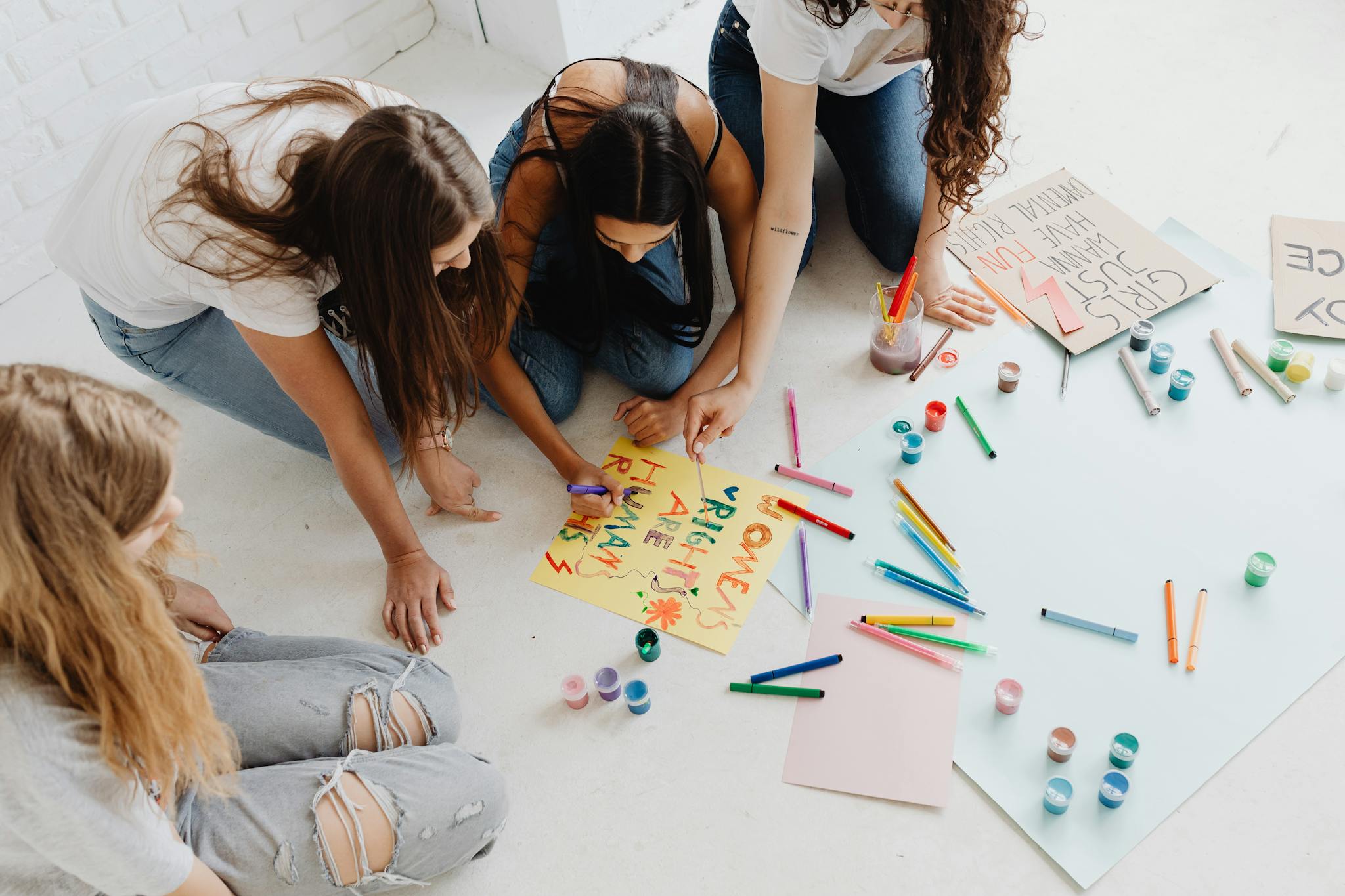 Group of women designing artistic placards with colorful materials.