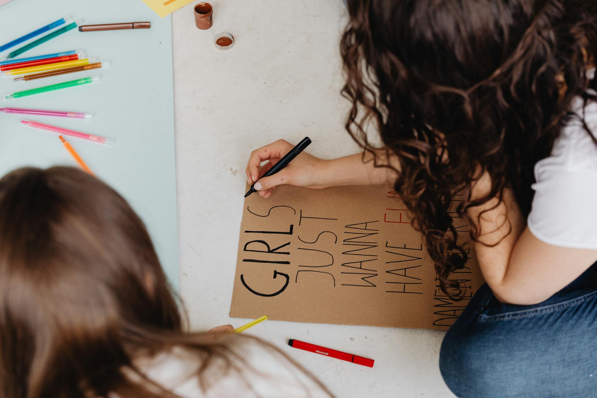 Two women create protest posters with markers, promoting creativity and activism.