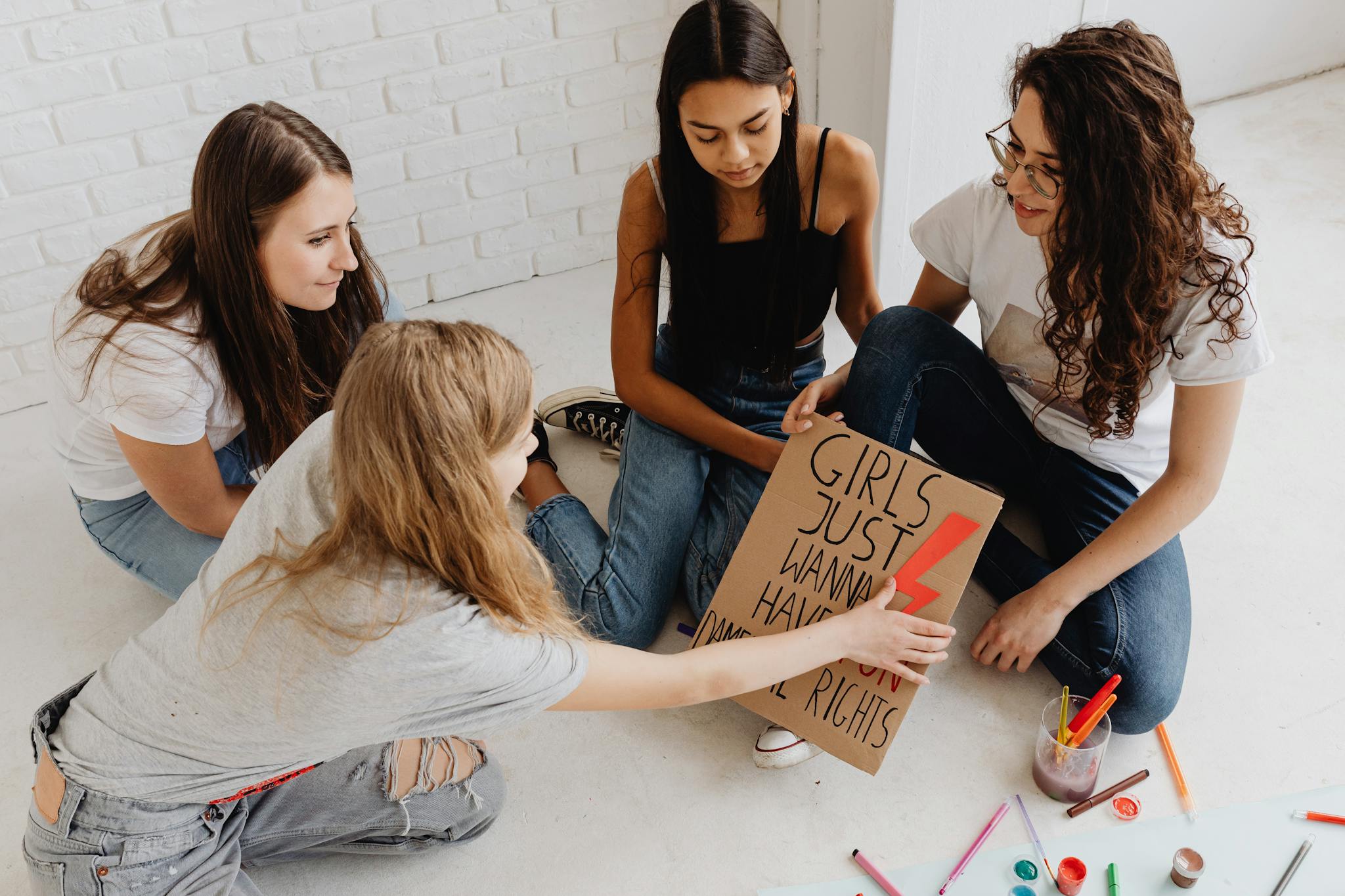 Young women engaged in creating activist signs for women's rights, promoting empowerment and equality.